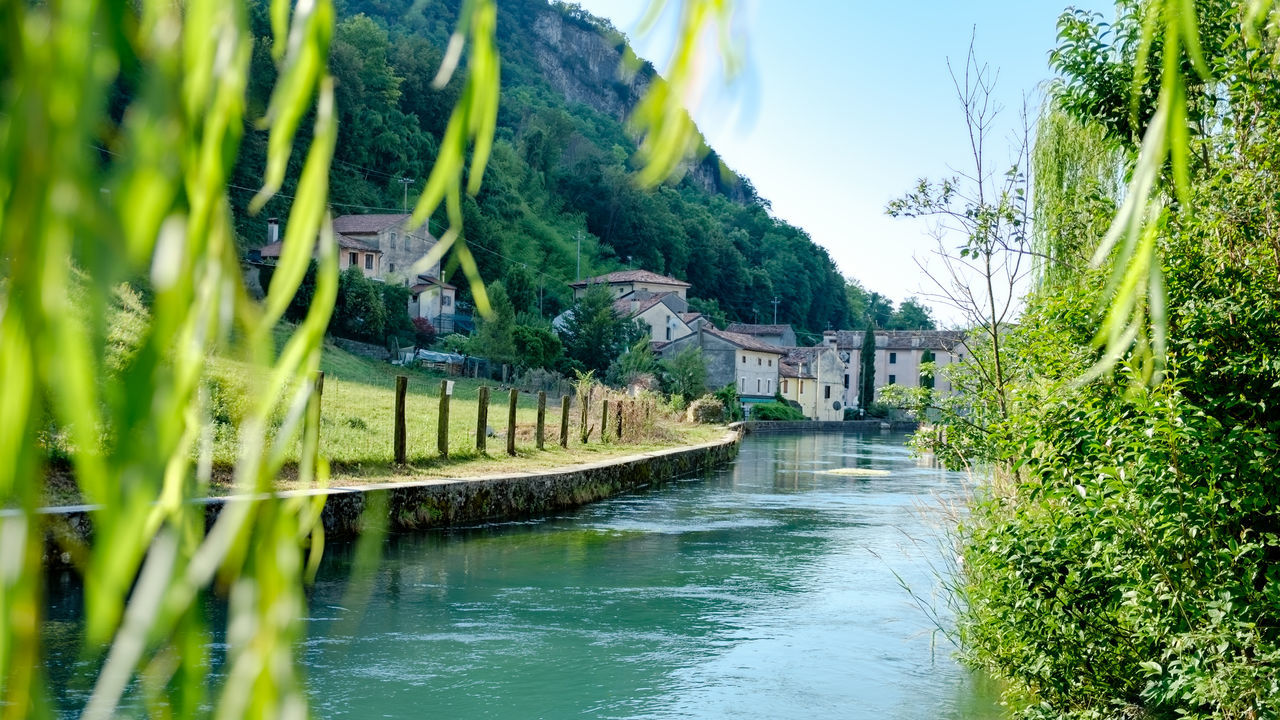 BRIDGE OVER RIVER AMIDST BUILDINGS AGAINST SKY