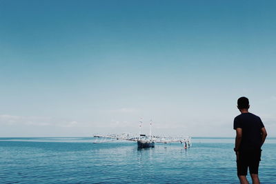 Rear view of man standing by sea against sky