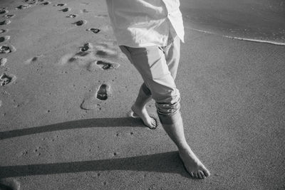 Low section of man walking at beach