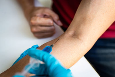 Cropped hands of doctor injecting syringe to man in hospital