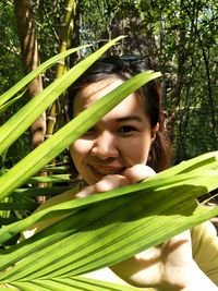 Portrait of young woman with green leaves