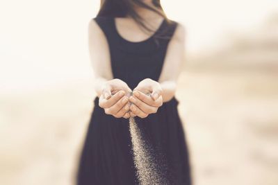 Midsection of woman playing with sand on sunny day