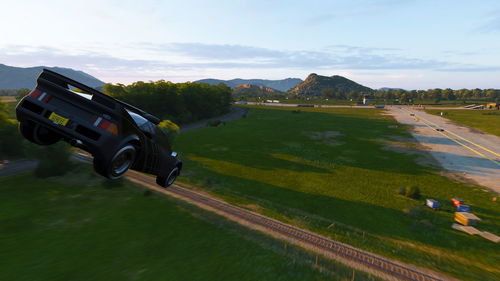 Cars on road amidst field against sky