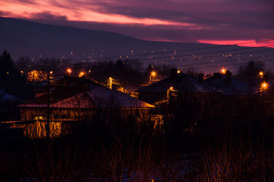 Illuminated cityscape against sky at dusk