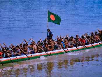 Group of people rowing boat in lake