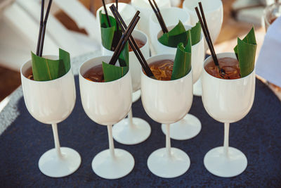 White glasses with tropical cocktails decorated with black straws and banana leaves