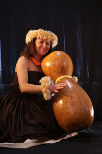 Portrait of young woman sitting on pumpkin