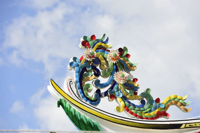 Low angle view of multi colored umbrellas on building against sky