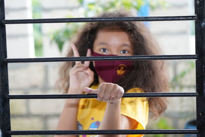Portrait of young woman holding railing against window