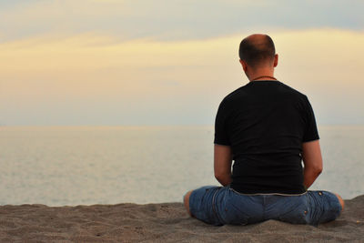 Rear view of man looking at sea against sky