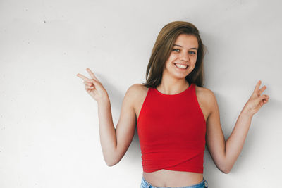 Portrait of a smiling young woman standing against wall