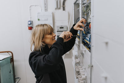 Smiling female electrician at work