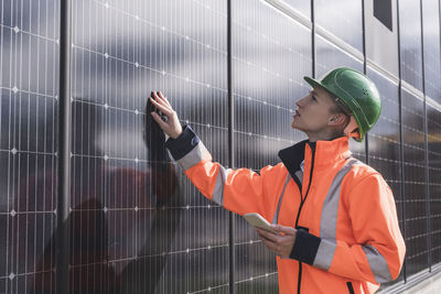 Young female engineer with smart phone examining solar panels