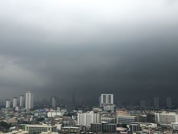 Buildings in city against storm clouds