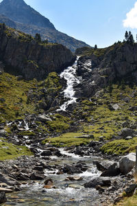 Scenic view of stream flowing through rocks against sky