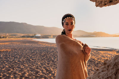 Portrait of woman standing on beach against sky