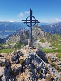 Cross on rock against sky
