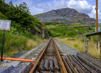 Railroad tracks by mountain against sky