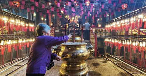Rear view of woman standing against illuminated building