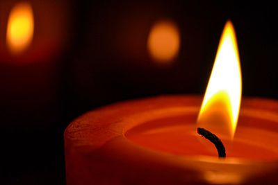 Close-up of lit candle in darkroom