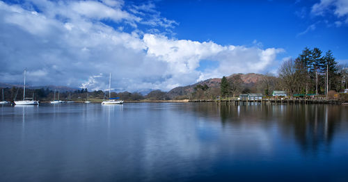 Sailboats moored at harbor against sky