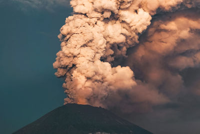 Low angle view of smoke emitting from volcanic mountain against sky