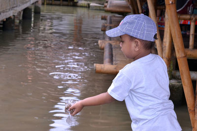 Boy feeding fish in pond