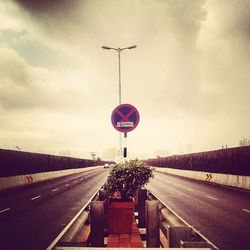 Road sign against cloudy sky