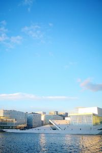 Buildings by sea against blue sky