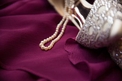 Close-up of pearl necklace and high heels on textile