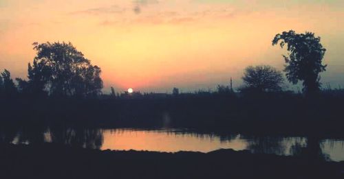 Reflection of trees in lake during sunset