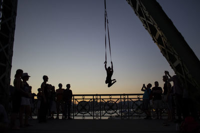 People looking at man performing stunt against sky