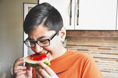 Young man eating watermelon slice at home