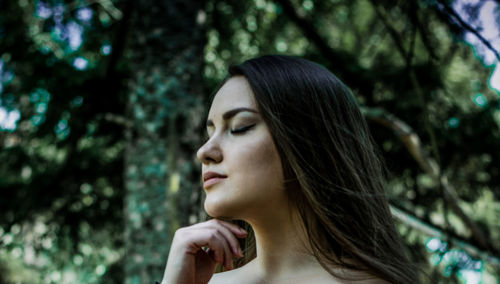 Young woman with closed eyes against trees