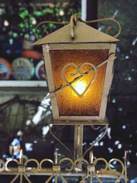 Close-up of illuminated light bulb decorated by heart 