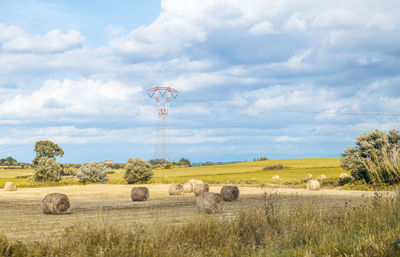 Hay bales on field against sky