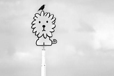 Close-up of bird perching on pole against sky