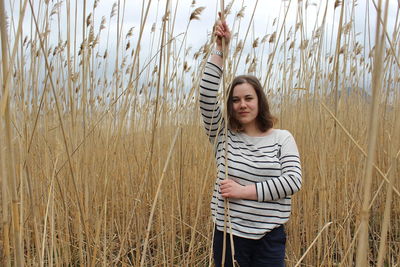 Portrait of a young girl in an outdoor field against a backdrop of wheat or tall grass.