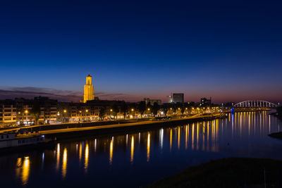 River by illuminated city against sky at night