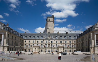 People in town square against buildings in city