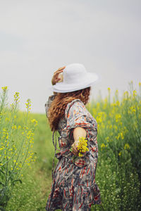 Side view of woman standing on field against sky