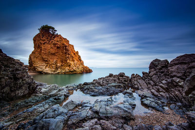 Rock formations by sea against sky