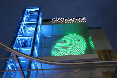 Illuminated information sign against sky at night