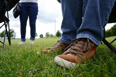 Low section of woman standing on grassy field