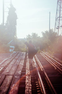 Rear view of man on railroad track against sky