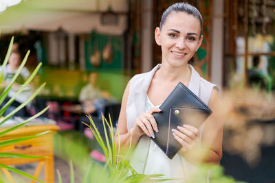 Beautiful woman smiling happy standing at city. notepad in hand standing.