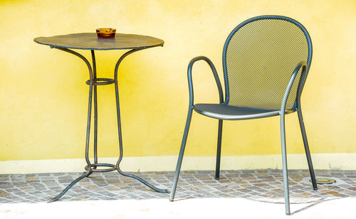 Empty chairs and table against wall