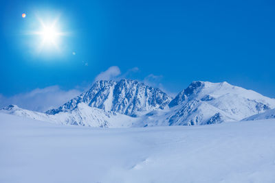 Scenic view of snowcapped mountains against blue sky