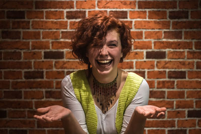 Young woman looking up against brick wall