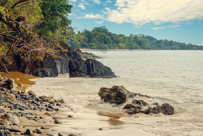 Scenic view of rocks on beach against sky